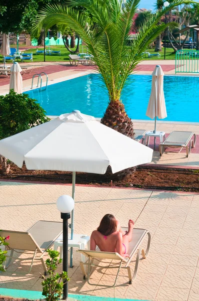 En vacker kvinna under parasoll är hållna nära vatten pool — Stockfoto