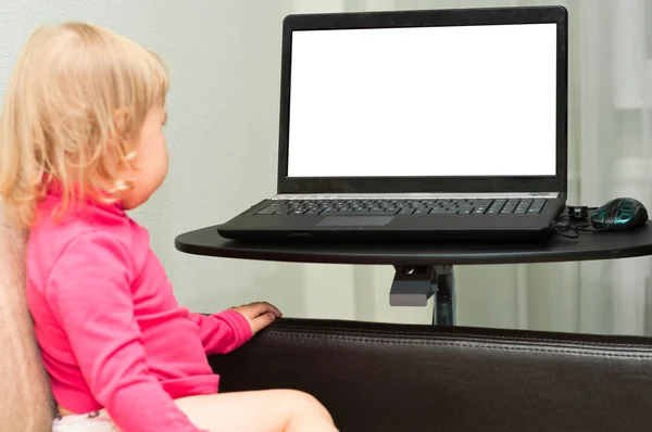 A small child is sitting with a laptop on the bed. — Stock Photo, Image