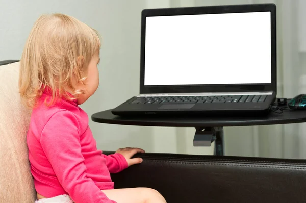 Ένα μικρό παιδί κάθεται με ένα laptop στο κρεβάτι. Λευκή οθόνη. επικεντρωθεί σε c — Φωτογραφία Αρχείου