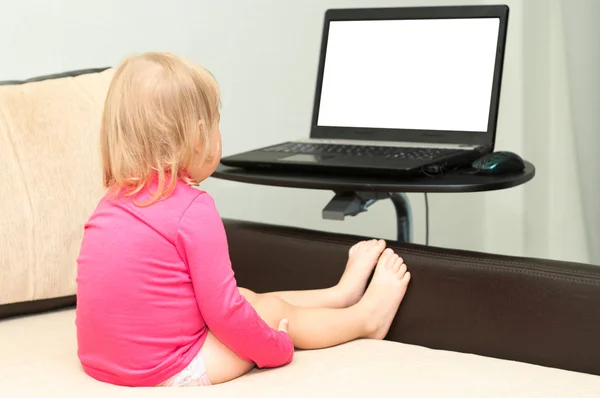 Criança está sentada com um laptop na cama. — Fotografia de Stock