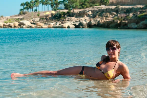 Giovane bella ragazza sdraiata su una spiaggia di sabbia vicino alla riva blu del mare — Foto Stock