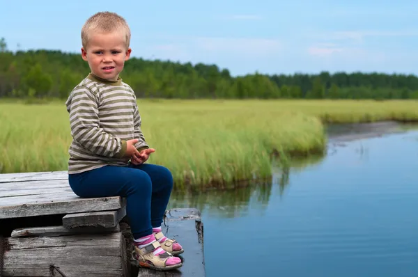 小男孩坐在湖边孤独的岩石上 他是在忧郁中 — 图库照片