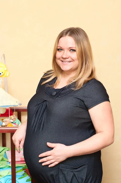 Pregnant young woman standing near baby`s bed. — Stock Photo, Image