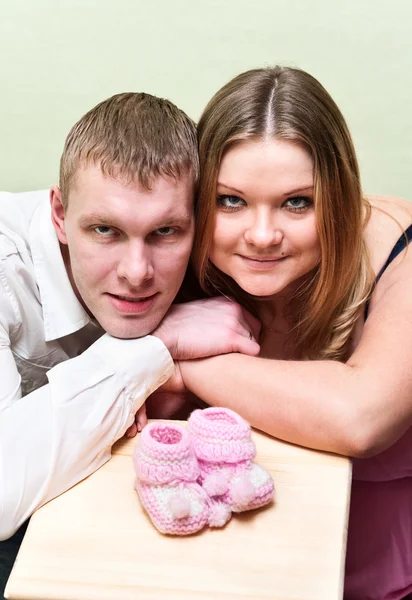 Pregnant woman with her husband looking at baby`s booties — Stock Photo, Image