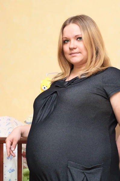 赤ちゃんのベッドの近くに立っている妊娠中の若い白人女性 — ストック写真