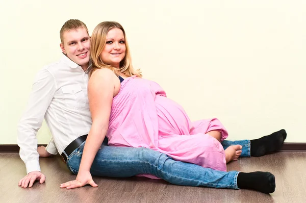 彼女の夫と空の部屋の床に座って妊娠中の女性 愛する若いカップル — ストック写真