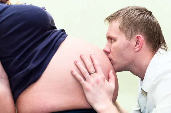 Беременная женщина с мужем, целующим живот . — стоковое фото