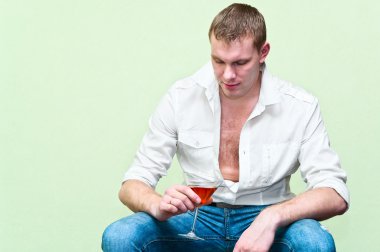 Handsome man sitting with glass of alcohol. Caucasian gay clipart