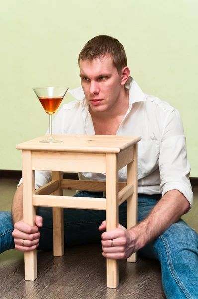 П'яний чоловік сидить на підлозі зі склянкою алкоголю — стокове фото