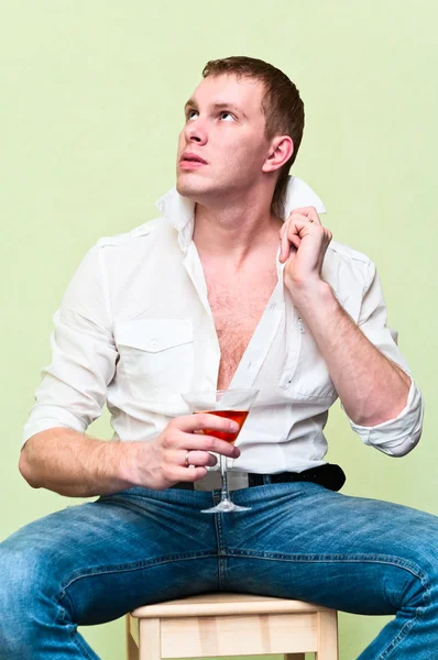 Красивый мужчина, сидящий со стаканом алкоголя . — стоковое фото