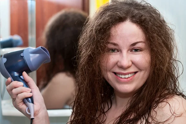 Joven mujer caucásica con pelo rubio marrón rizado sosteniendo secador de pelo —  Fotos de Stock