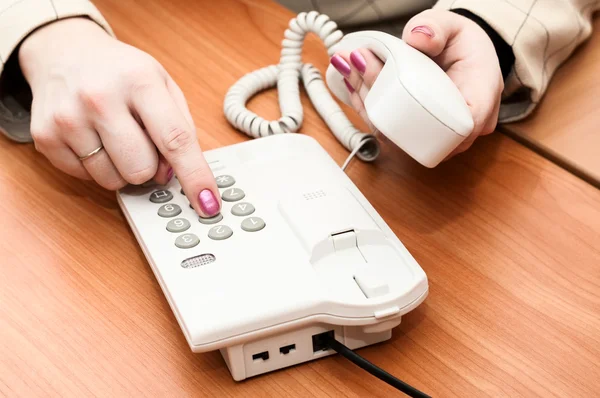 Women's hands dial a telephone number on the white telephone — Stock Photo, Image