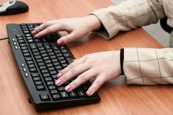 Manos femeninas escribiendo en un teclado negro — Foto de Stock