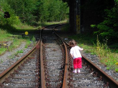 Girl at Railroad tracks at a train station clipart