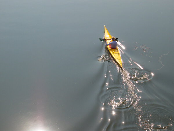Man rows a yellow sea kayak