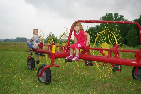 Kinderen zittend op gele en rode haymaker — Stockfoto