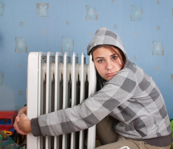 Chica joven está sentado cerca del calentador —  Fotos de Stock