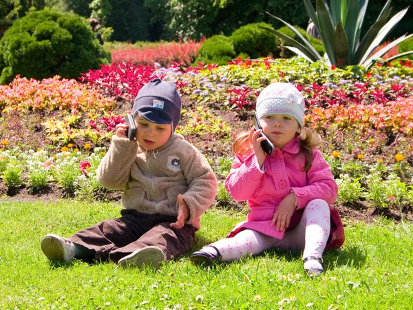 Boy and girl playing in the park with mobile phones — Stock Photo, Image