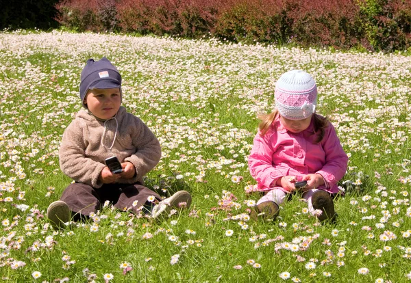 Chlapec a dívka si hraje v parku s mobilními telefony — Stock fotografie