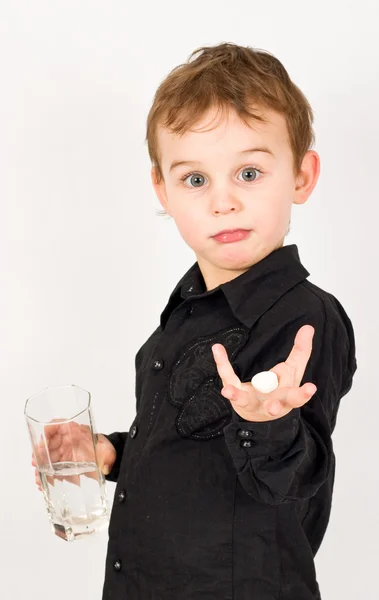 Niño mantenga píldora y vidrio en las manos — Foto de Stock