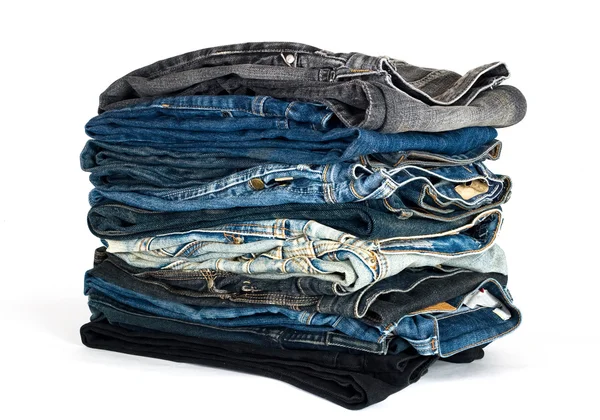Pilha de várias calças de ganga isoladas em branco — Fotografia de Stock
