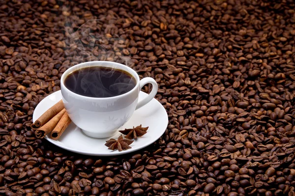 Beyaz fincan sıcak kahve kahve çekirdekleri üzerine — Stok fotoğraf
