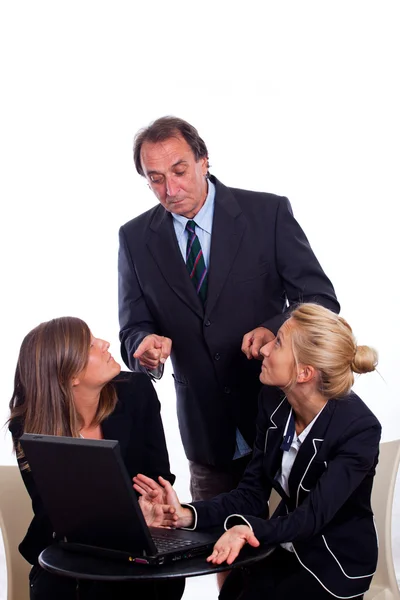 Baas vertoornd op twee zakenvrouw chatten in plaats van werken — Stockfoto