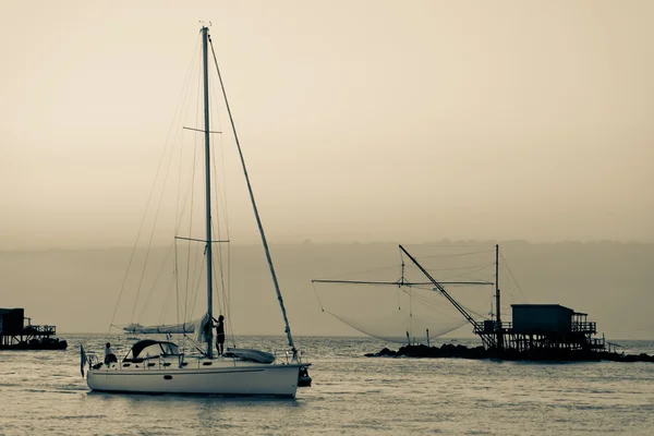 Barco à vela e rede tradicional do pescador ao pôr-do-sol — Fotografia de Stock