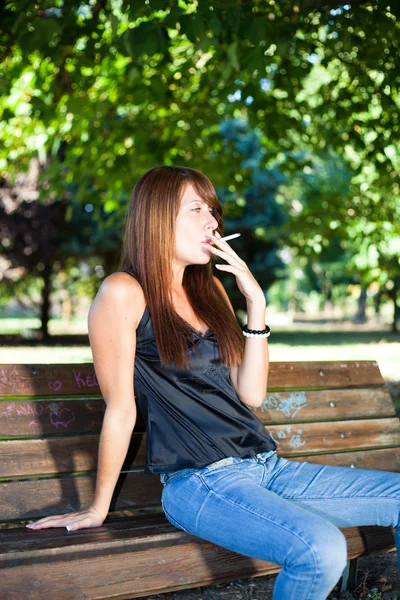 Молодая женщина курит на открытом воздухе — стоковое фото