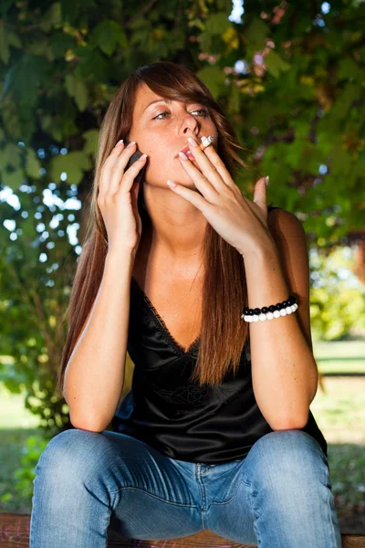 Mujer joven habla por teléfono y fuma — Foto de Stock