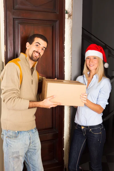 Homem recebe uma caixa de mulher jovem com chapéu de Natal — Fotografia de Stock