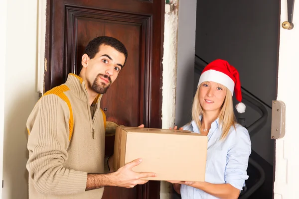 Мужчина получает коробку от молодой женщины в рождественской шляпе — стоковое фото