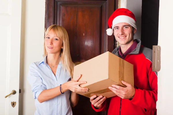クリスマス帽子と若い女性のためのボックスの配達の少年 — ストック写真