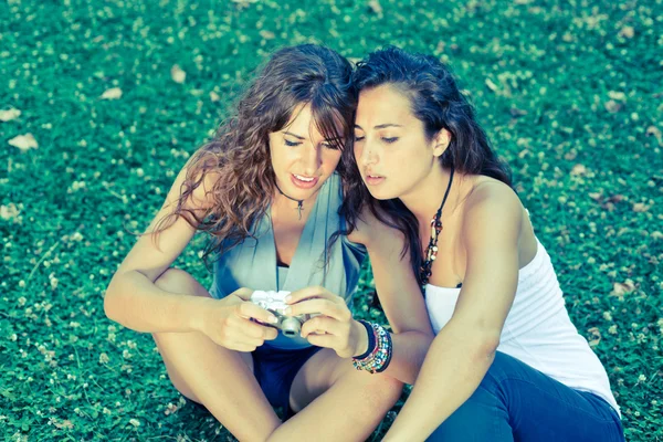 Dwie dziewczyny w parku, patrząc na zdjęcia w aparacie — Zdjęcie stockowe