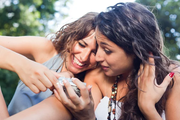 Две девушки в парке смотрят фотографии в камеру — стоковое фото