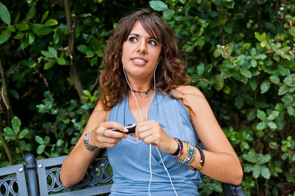 Mujer joven escuchando música en el parque — Foto de Stock
