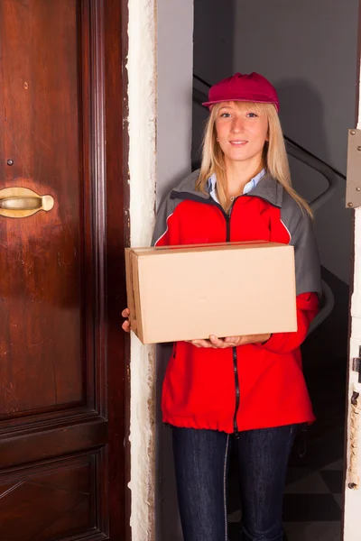 Vrouwelijke courier bij de deur met een doos — Stockfoto