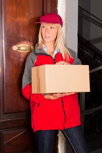 Vrouwelijke courier bij de deur met een doos — Stockfoto
