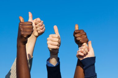 Multiracial Thumbs Up Against Blue Sky clipart