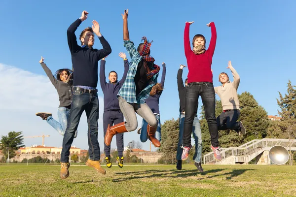 公園でジャンプ幸せな大学生のグループ — ストック写真