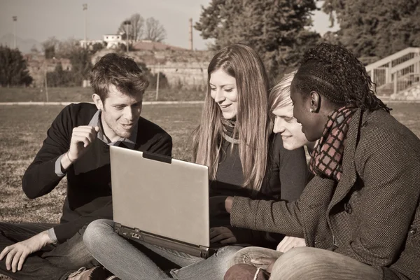 Vysokoškoláky s počítačem v parku — Stock fotografie