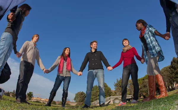 Mnohonárodnostní mladí drží za ruce v kruhu — Stock fotografie