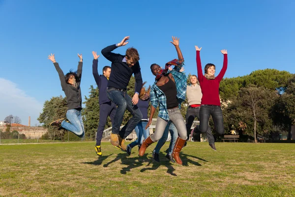 Grupo de estudantes universitários felizes saltando no parque — Fotografia de Stock