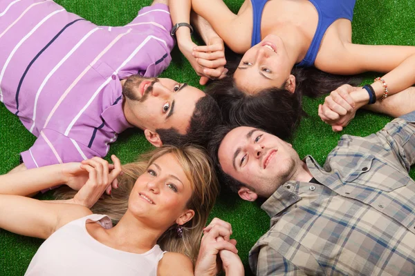 Giovane sdraiato su un terreno verde con le mani unite — Foto Stock