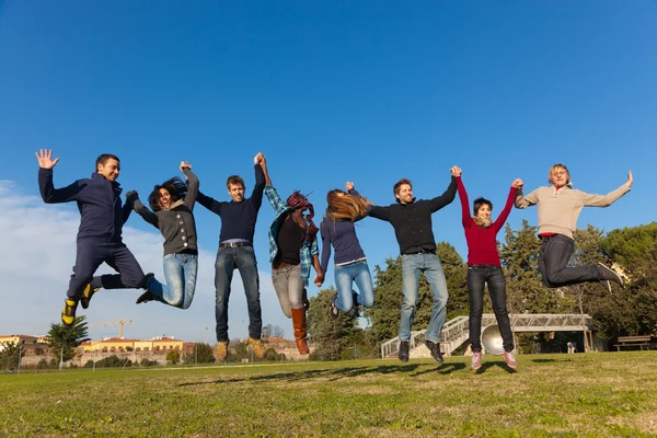 Grupa studentów szczęśliwy, skoki w parku — Zdjęcie stockowe