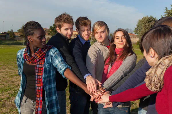 Estudiantes universitarios felices con manos en la pila — Foto de Stock