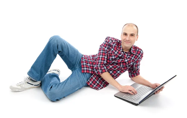 Χαρούμενος νεαρός άνδρας σερφ για φορητό υπολογιστή, που βρίσκεται κάτω. — Φωτογραφία Αρχείου