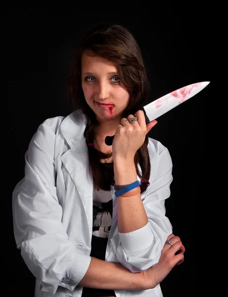 Arg sjuksköterska med blodig kniv över svart — Stockfoto