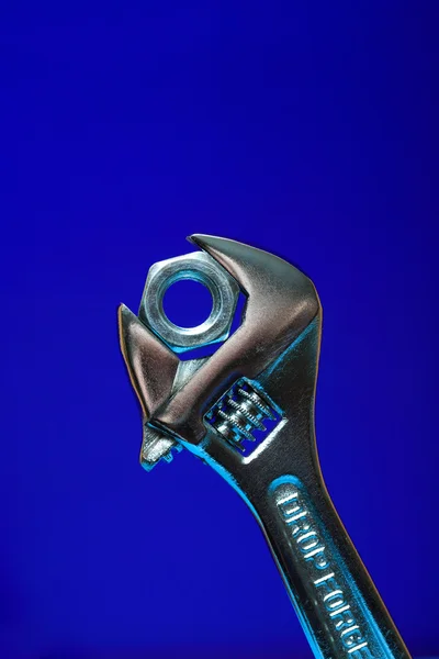 Extreme Closeup Adjustable Wrench Gripping Screw Nut Blue Background — Stock Photo, Image