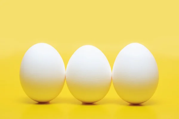 Three White Hen Eggs Standing Vertical Yellow Background — Stock Photo, Image